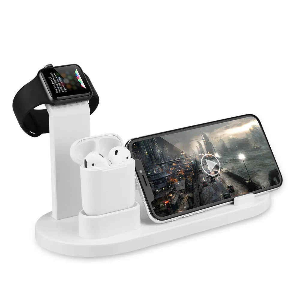 White three-in-one headphone charging stand dock on a desk with a USB cable.