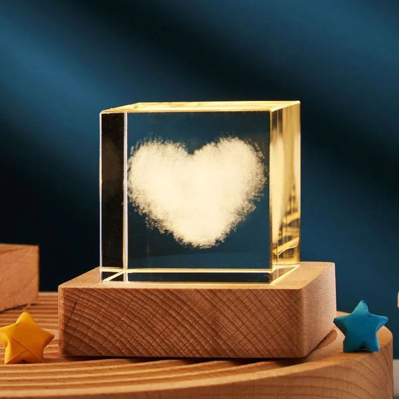 Transparent glass cube night lamp projecting a warm nebula light pattern on a desk.