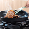 Green silicone fish spatula with 1mm thin slotter blade and hanging hole on a kitchen counter