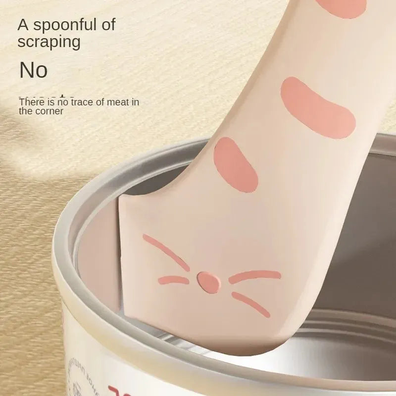 Grey silicone pet food can sealing lid and mixing spoon with integrated can opener on a white background.
