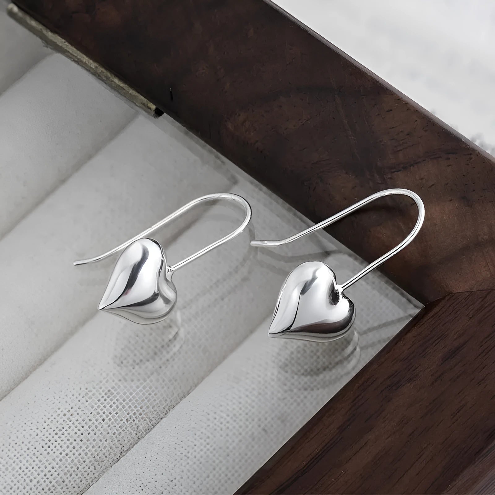 Silver-coloured heart-shaped earrings with three-dimensional glossy design and Korean-style aesthetic