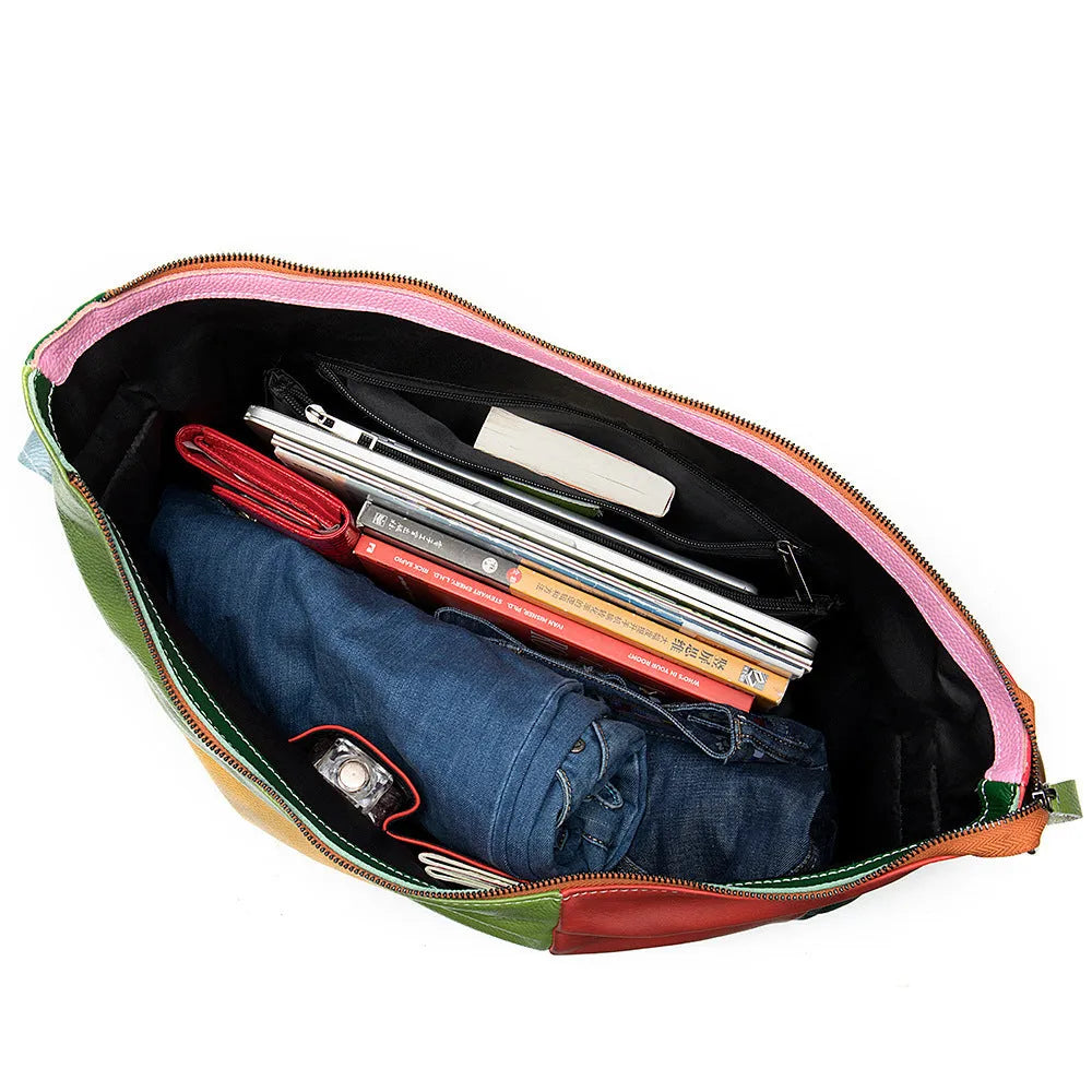 Brown cowhide leather travel bag with stitching, shown as a crossbody bag with a laptop and iPad inside.