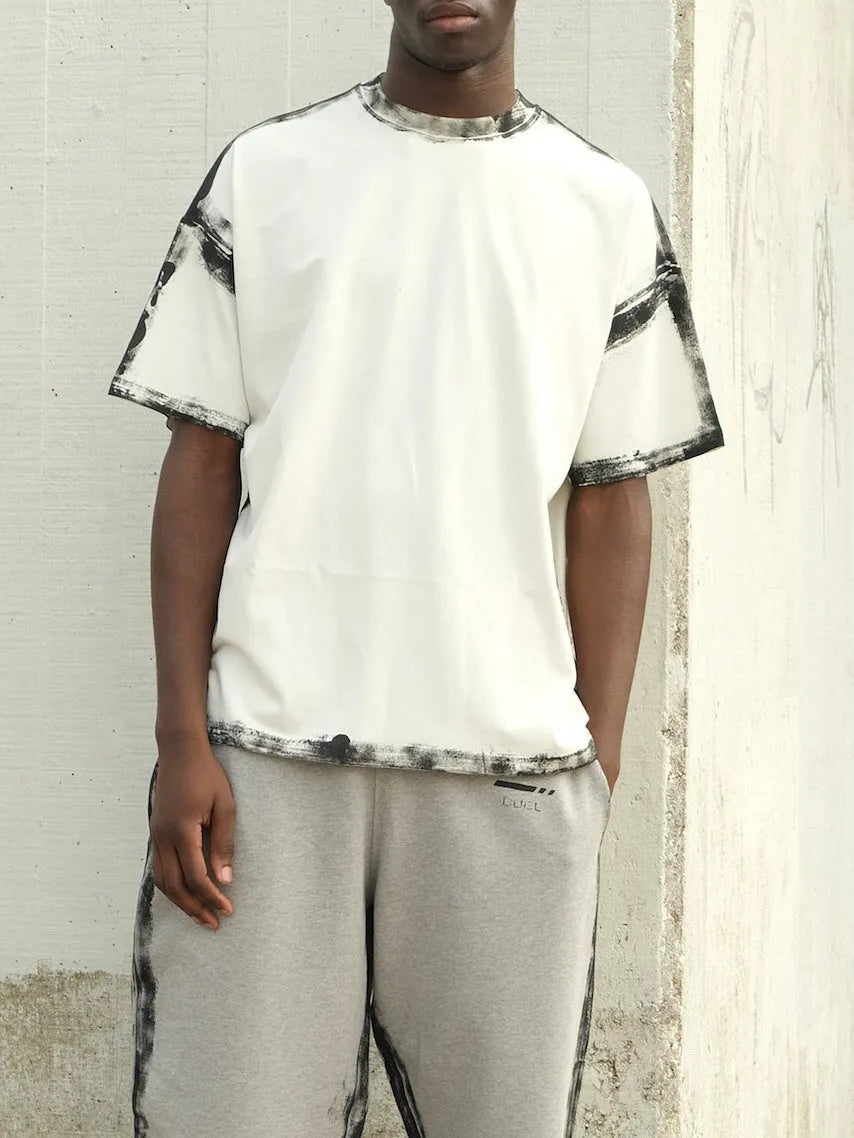 White casual short sleeve top with draped design and printed pattern, laid flat.