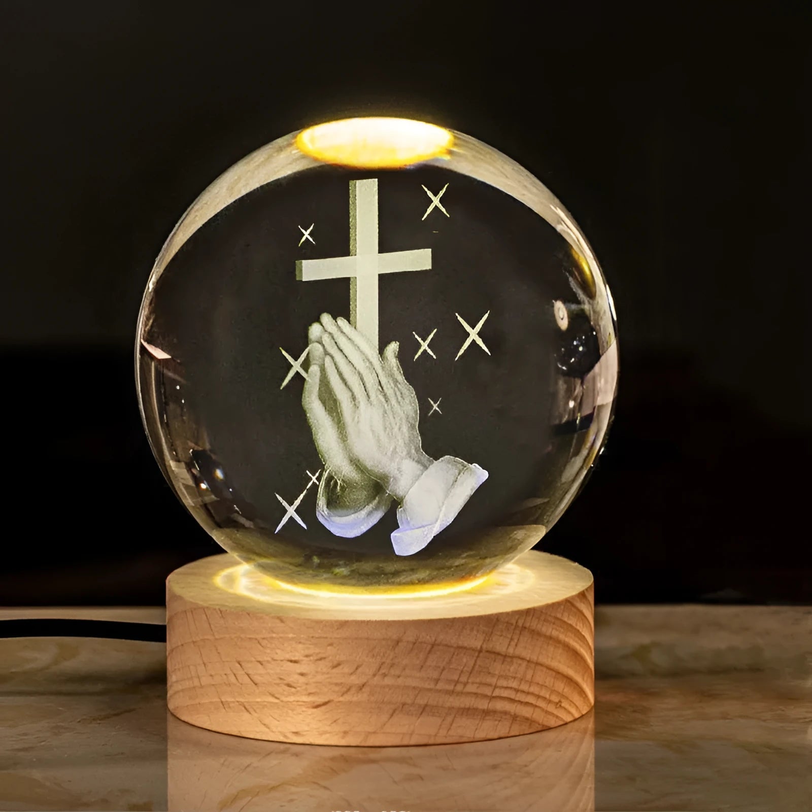 White crystal ball desk ornament on a solid wood base with a warm light, showing religious motif options.