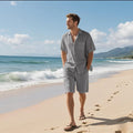 Man wearing a light blue linen blend short-sleeve shirt and matching shorts, a casual two-piece beach outfit set.
