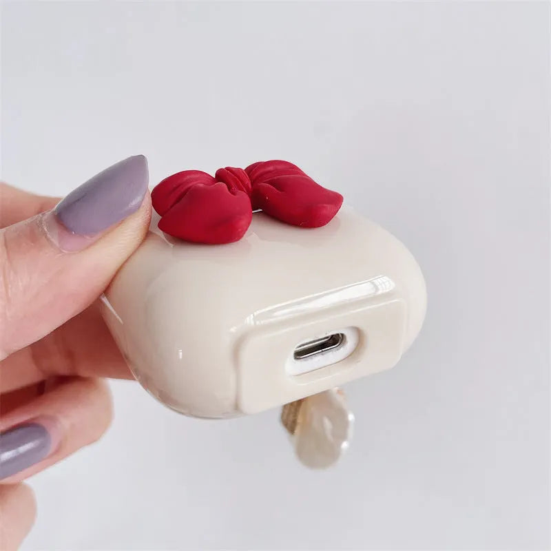 Beige AirPods case with red bow decoration, clamshell design for AirPods Pro and AirPods 3 models