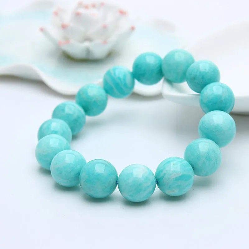 A single green amazonite bead bracelet on an elastic cord, shown in a natural setting.