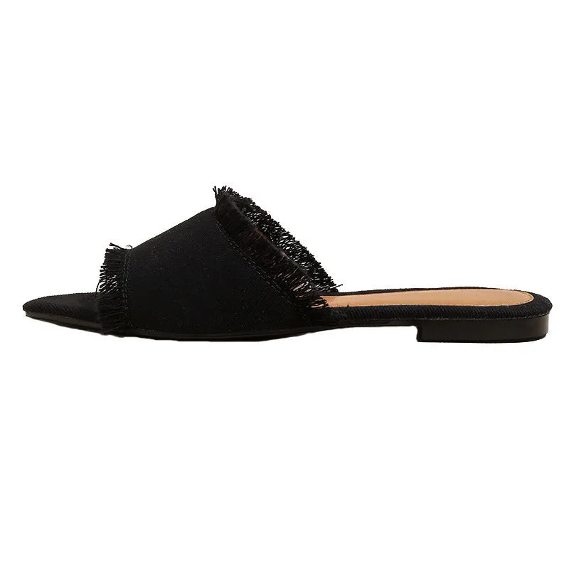 Women's apricot denim flat slippers with a tassel on the front, showing leather lining and lightweight PVC sole.