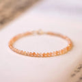 Close-up of a women's bracelet with small 3mm round sunstone beads on a string.