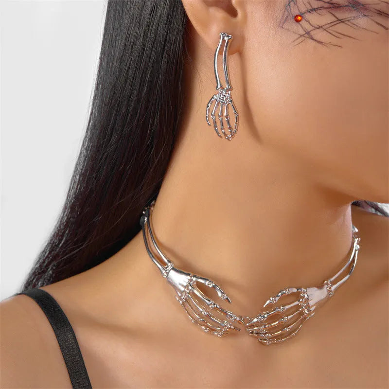 Silver alloy skull and ghost claw necklace with matching earrings set on a dark background.