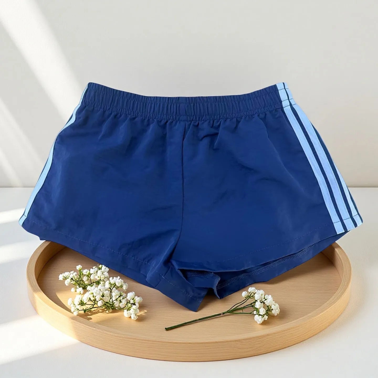 Men's navy blue high-waist nylon sports shorts laid flat, showing casual style and micro-elastic fabric.