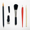 Scratch art tool kit with scraping pens, brushes, repair liquid, and bamboo sticks on a craft table.