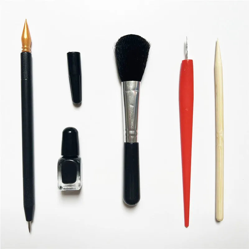 Scratch art tool kit with scraping pens, brushes, repair liquid, and bamboo sticks on a craft table.
