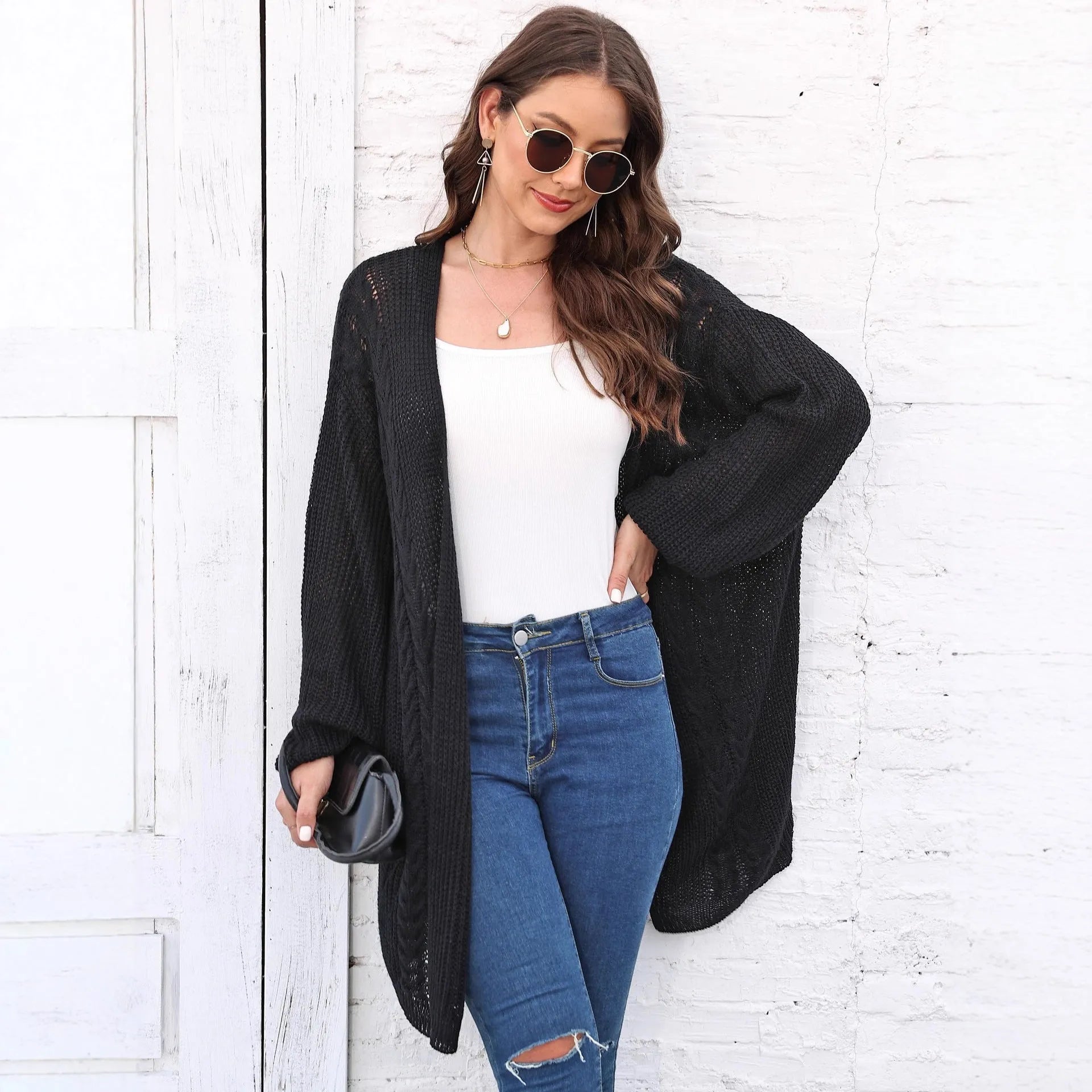 Women's loose brown acrylic sweater coat hanging, showing solid colour and knit texture.