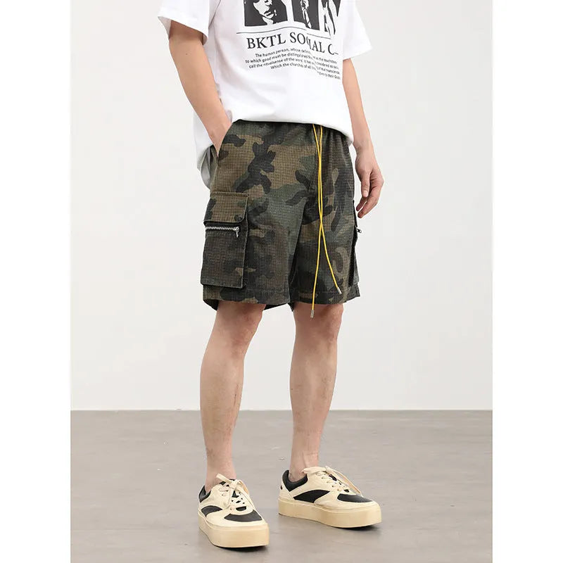 Men's camouflage multi-pocket cropped work shorts laid flat showing cargo pockets and camo pattern.