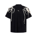 Black loose fit short-sleeve T-shirt with padded shoulders and decorative rivet ribbon detail on a hanger.