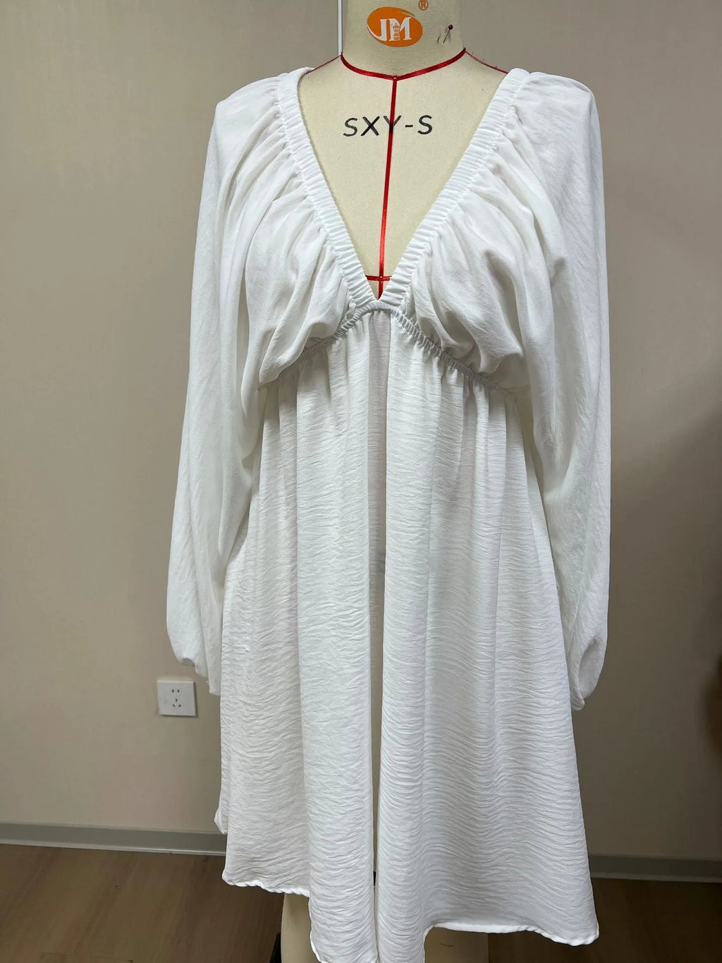 Women's apricot V-neck long-sleeve dress with puff sleeves and a flounce swing skirt on a hanger.