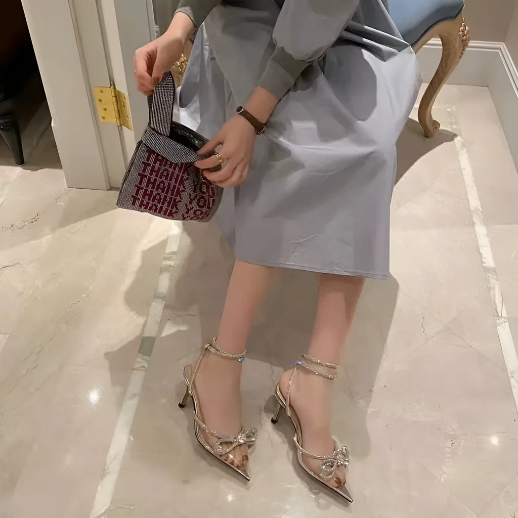 Women's black stiletto heel sandals with a silk back bandage and buckle fastening, shown from the side.