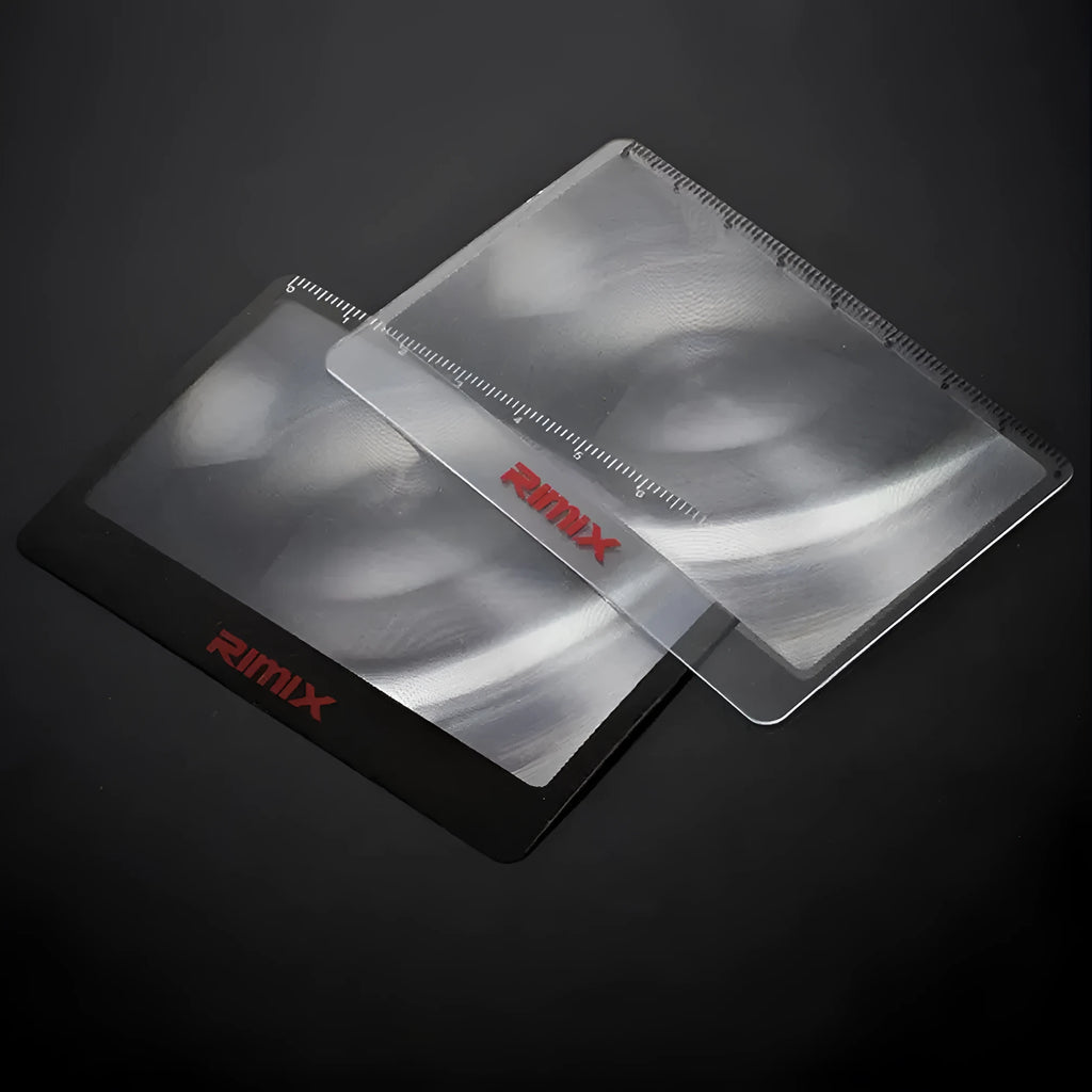 A thin, credit-card sized black plastic magnifier with a Fresnel lens, shown next to a bank card for scale.