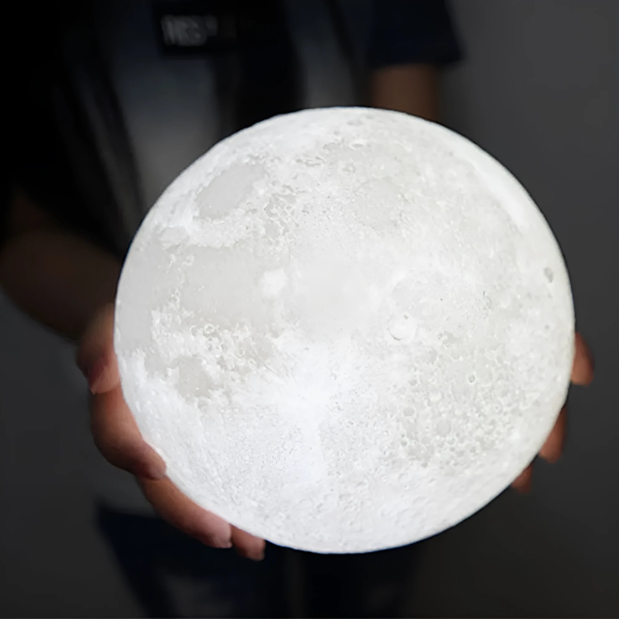 White 3D-printed moon lamp on a wooden stand with a visible textured surface.