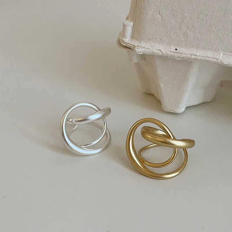 Geometric open ring with three-dimensional interlaced matte metal construction in gold or silver finish