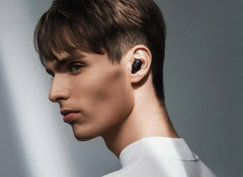 Redmi AirDots black true wireless earbuds and charging case on a table.