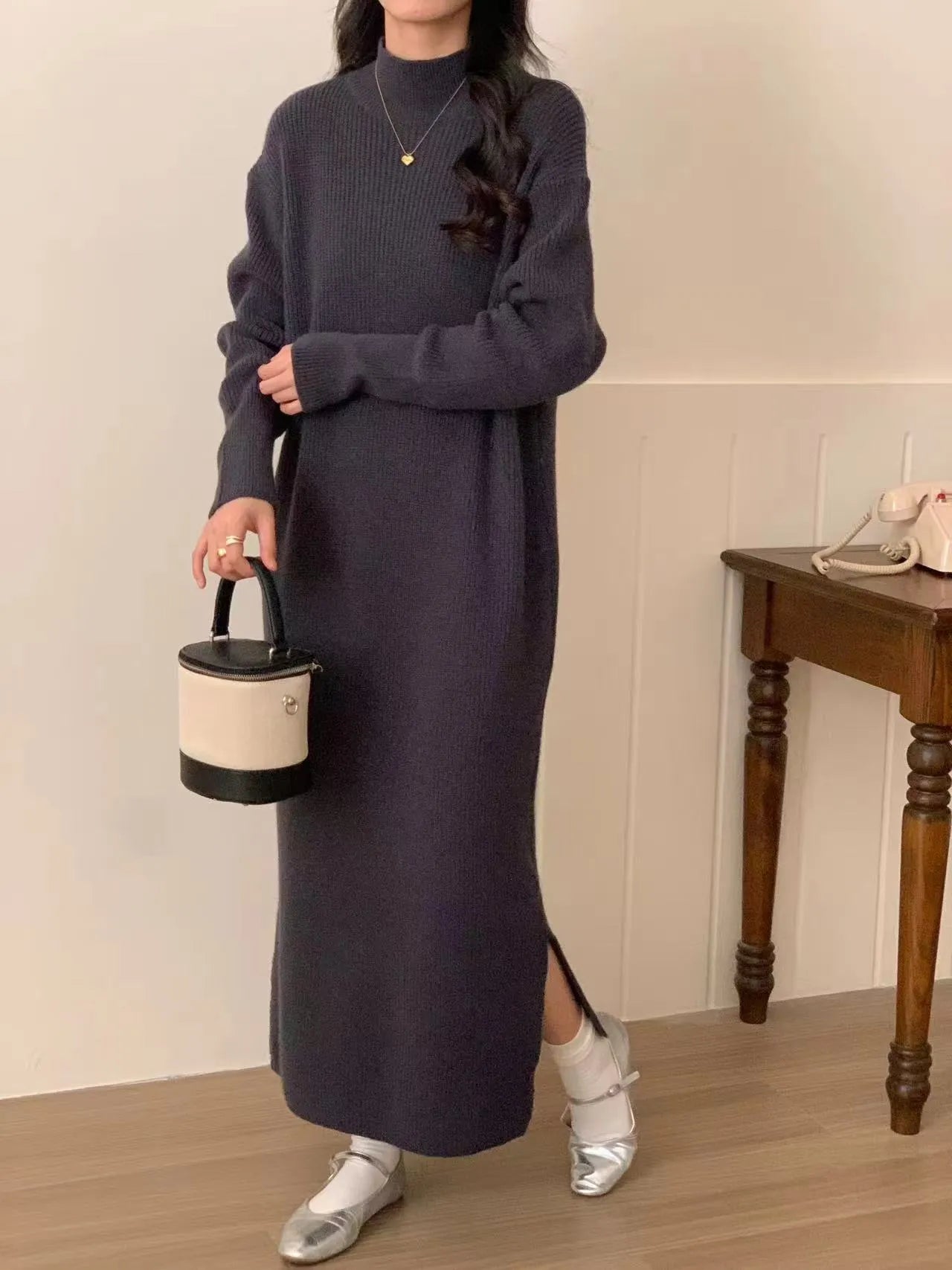 Woman wearing a milky white half turtleneck acrylic knit dress with a high waist and overknee A-line skirt.