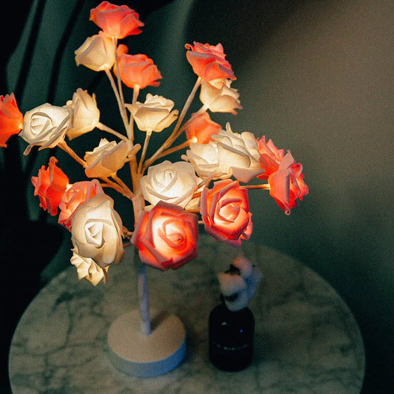 White and red rose shaped LED table lamp with bonsai tree base on a wooden table.