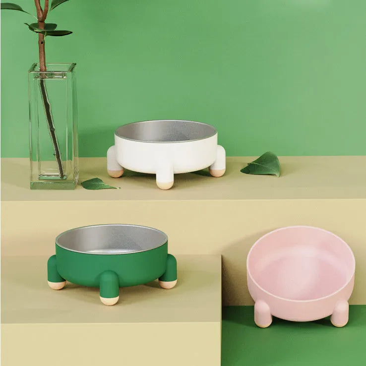 Green stainless steel pet bowl with non-slip base and high foot on a kitchen floor.