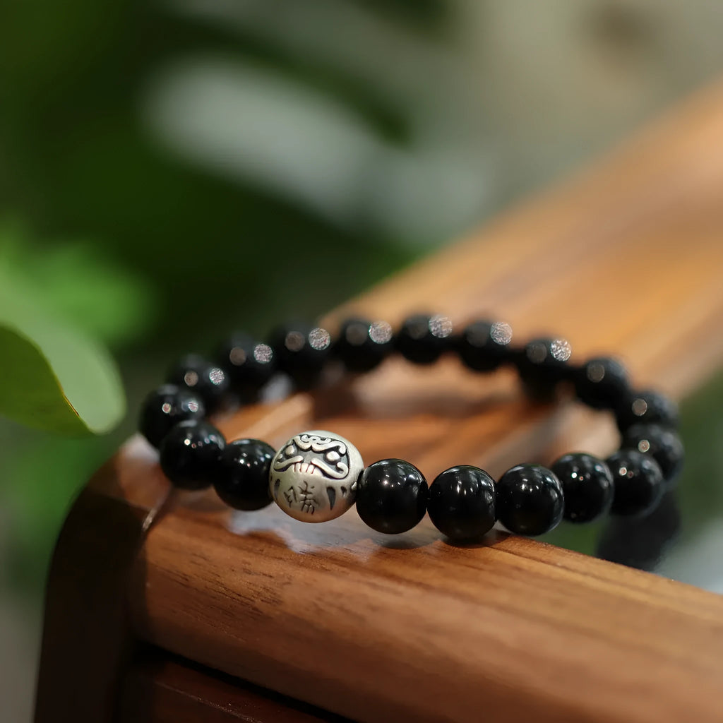 Natural black agate bead bracelet with a sterling silver clasp on a wrist.