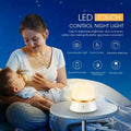 White rechargeable touch-control bedside night light with motion sensor on a table.
