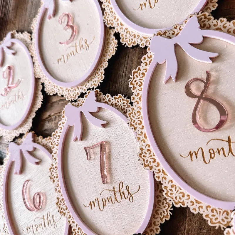Carved boxwood lace frame bow baby milestone card with ten number stickers on a white background