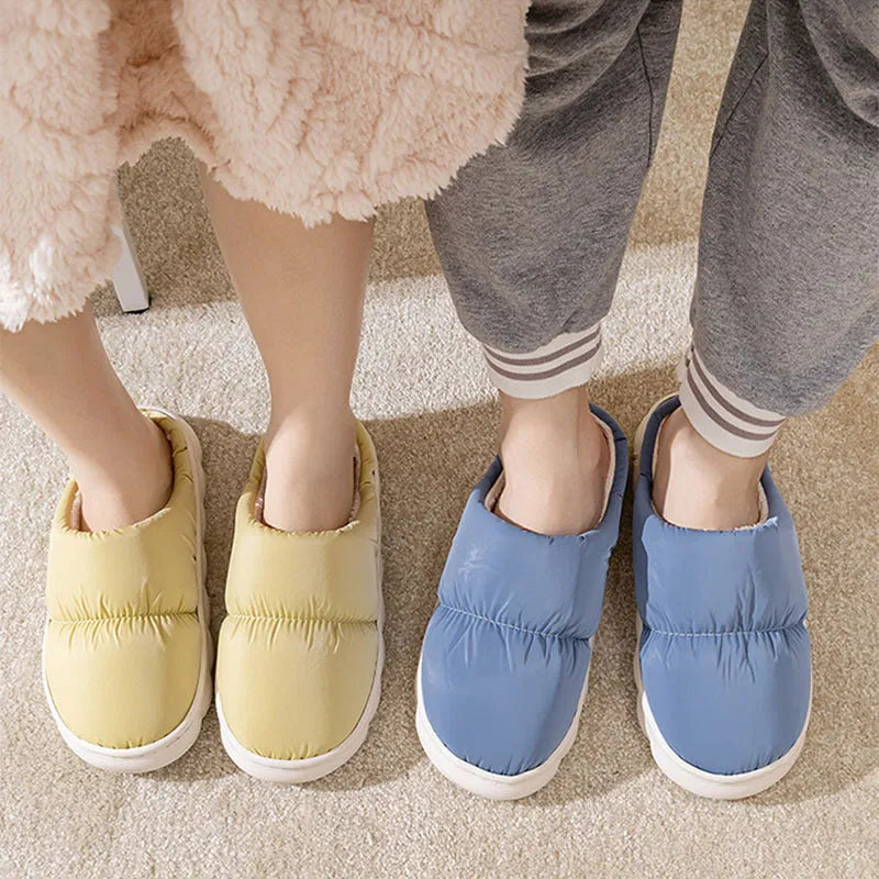 A pair of thick-soled house slippers with an artificial leather upper and plush lining, shown in a choice of colours.