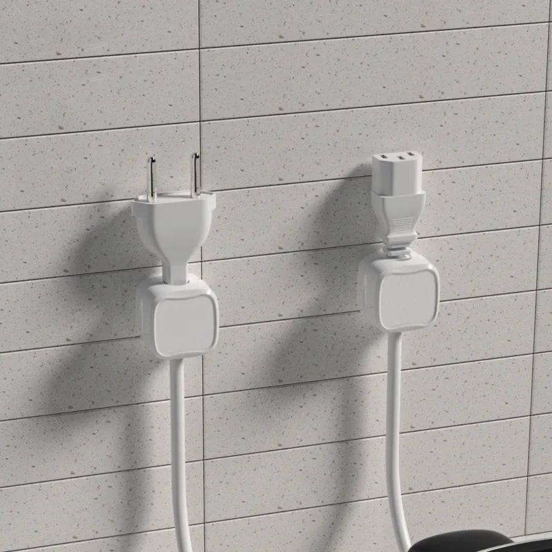 White and black magnetic adhesive cable clips holding a USB cable against a wooden desk.