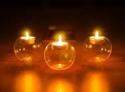 Handmade round hollow blown glass candle cup on a table.