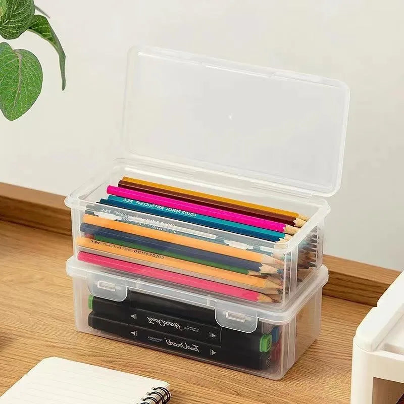 Transparent plastic stationery storage box containing colour pencils and drawing supplies