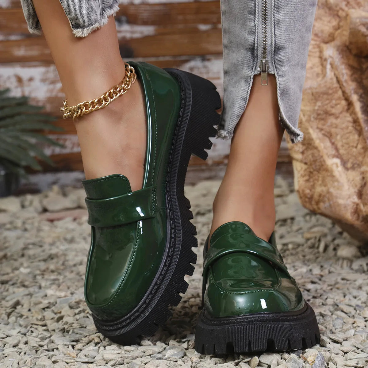 Black slip-on loafers with a chunky platform heel and thick rubber sole on a wooden floor.