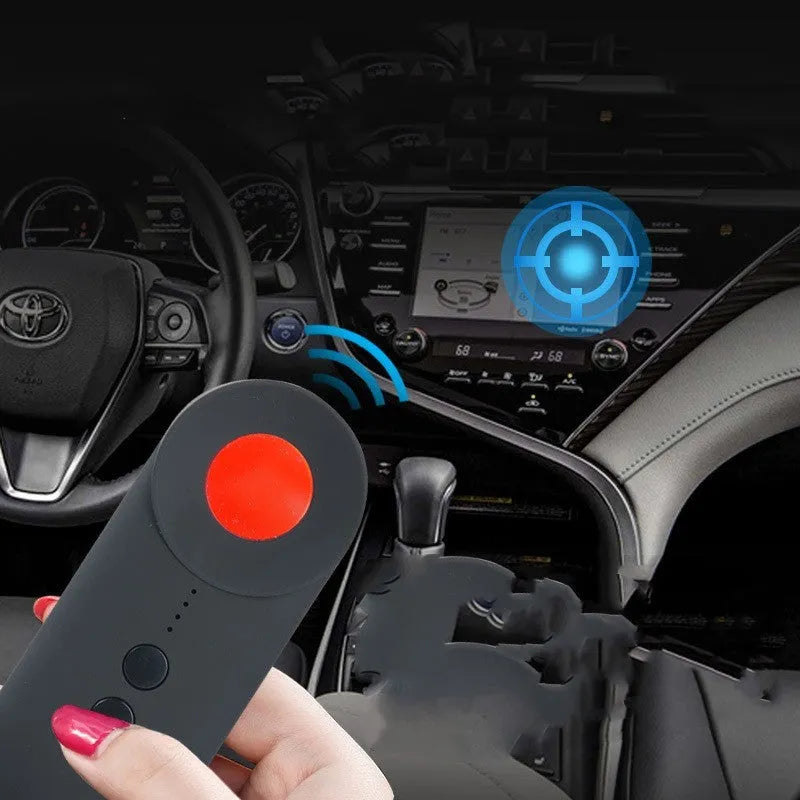 Black portable GPS and hidden camera detector with USB charging cable on a grey background.