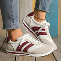 Wine red women's low-top sneaker with mesh upper, synthetic leather accents, and elastic cross straps on a flat rubber sole.