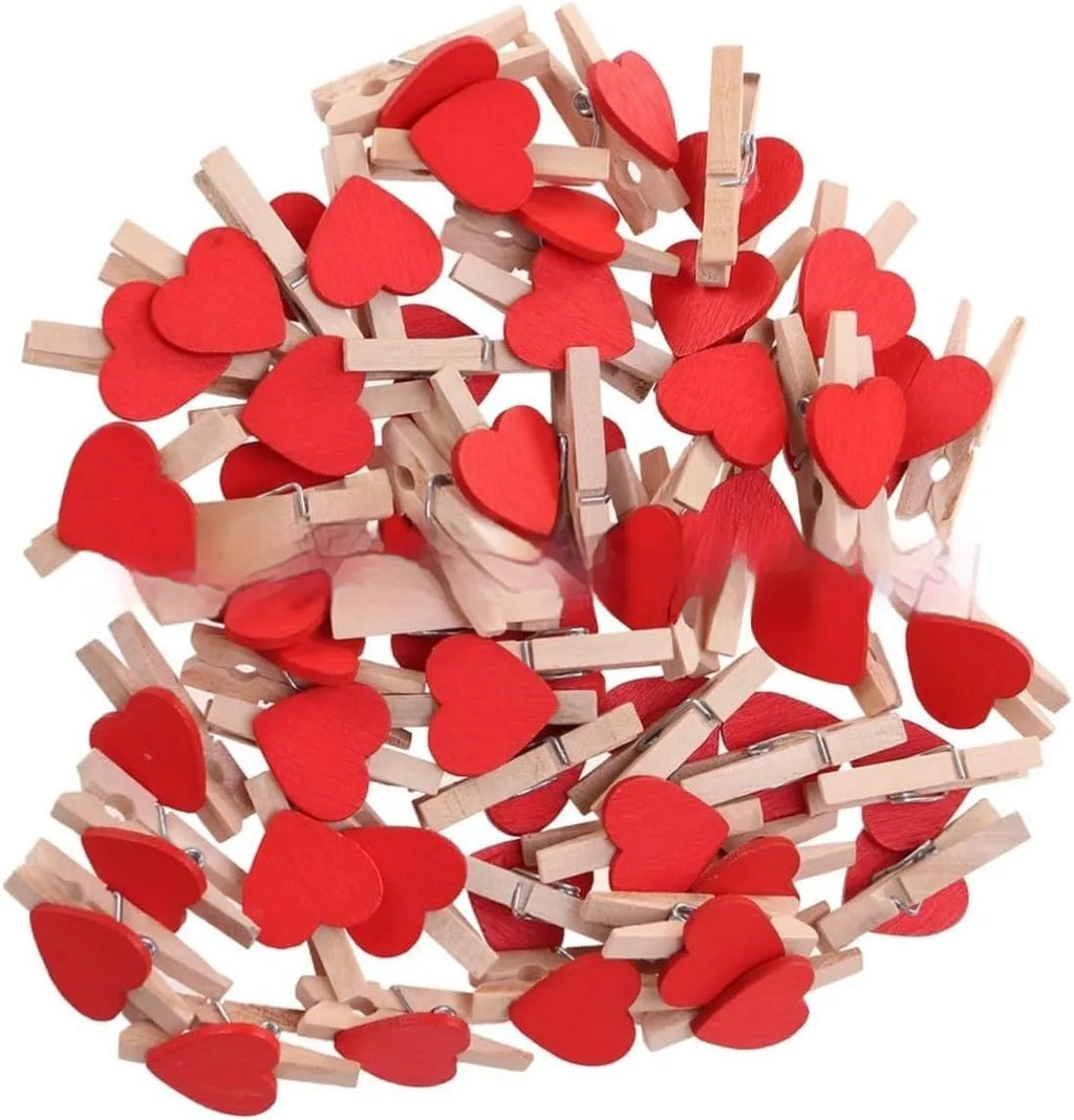 Five handmade solid wood heart-shaped hair clips in red, white, and pink on a wooden surface.