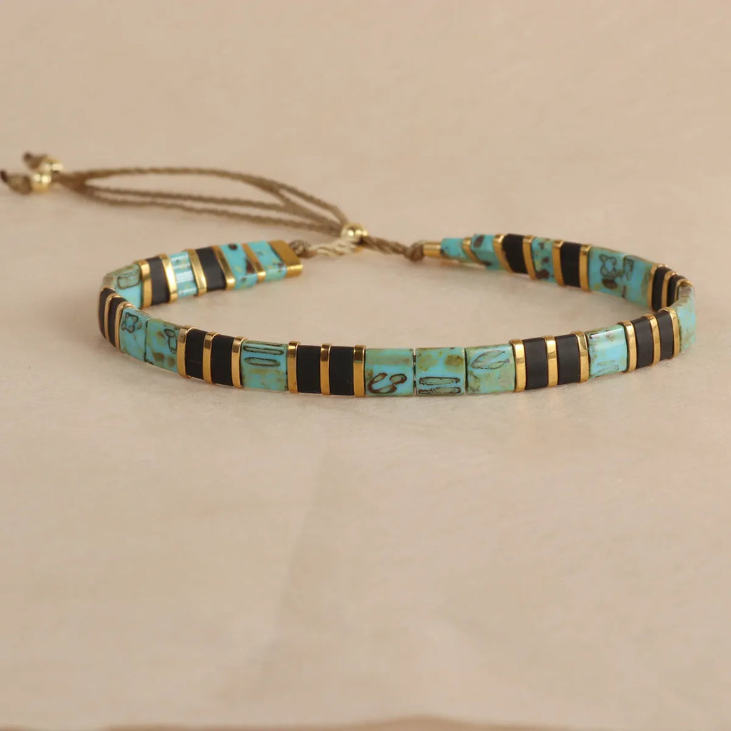 Geometric beaded bracelet with round elements in milky white, black, green, blue, or red.