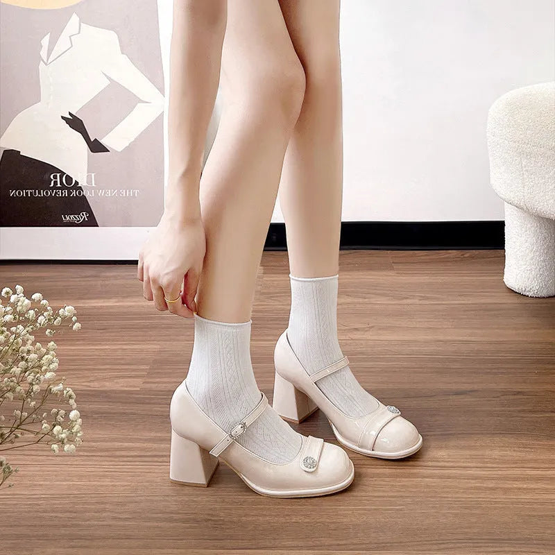 Women's black patent leather round toe shoes with a chunky block heel and buckle fastening.