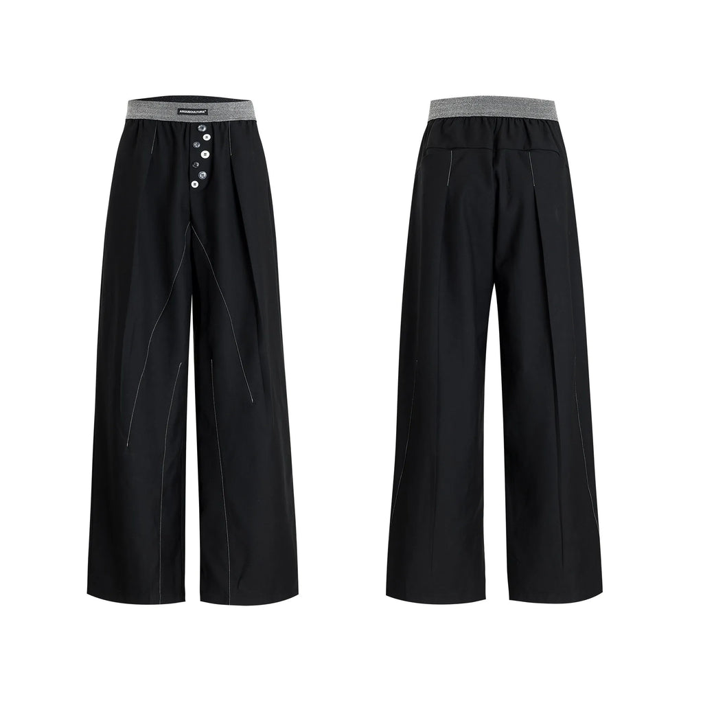 Men's black drooping straight-leg suit trousers with high waist and button detail.
