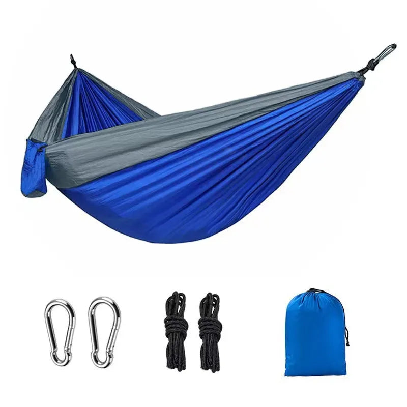 Blue parachute nylon outdoor camping hammock hung between two trees.