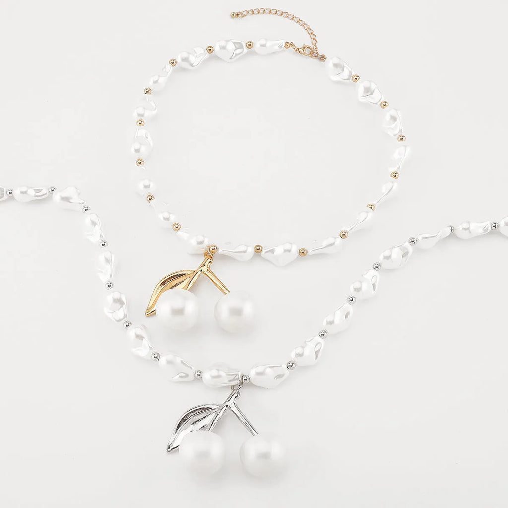 Gold coloured cherry fruit pendant necklace with imitation pearls on an adjustable chain.