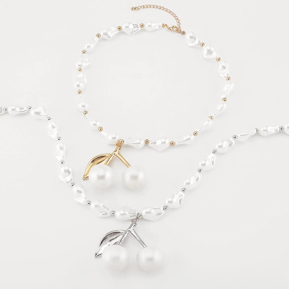 Gold coloured cherry fruit pendant necklace with imitation pearls on an adjustable chain.