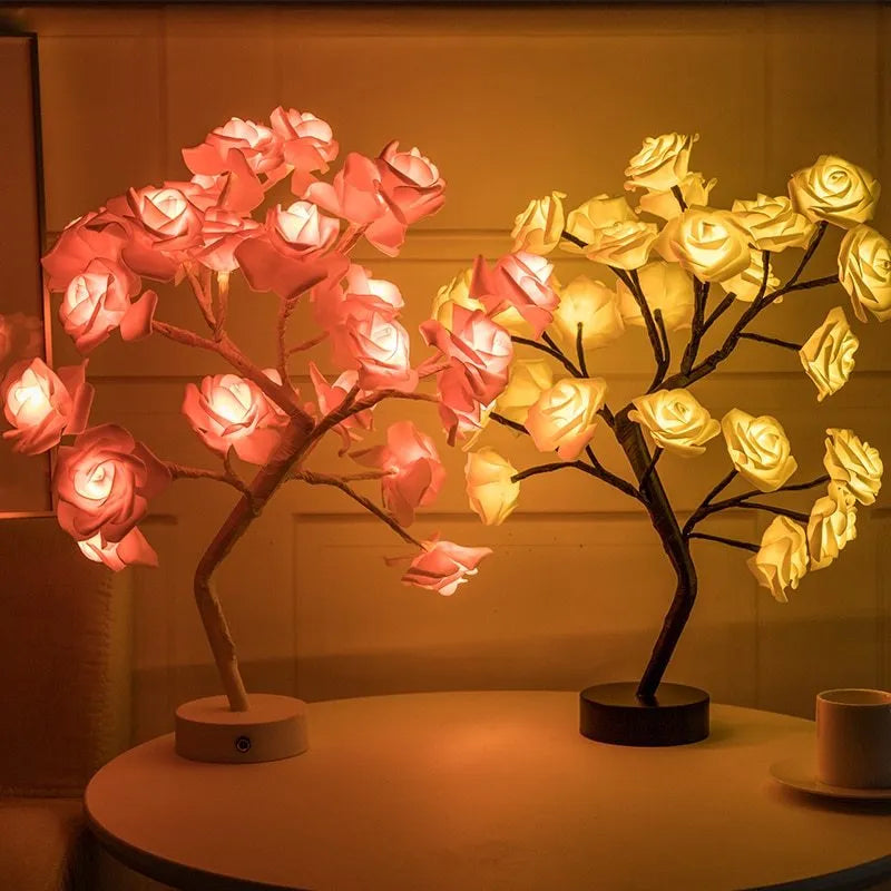 White and red rose shaped LED table lamp with bonsai tree base on a wooden table.