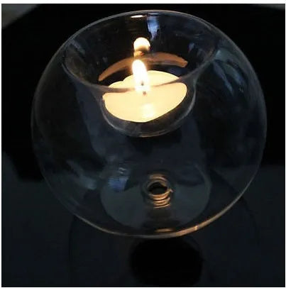 Handmade round hollow blown glass candle cup on a table.