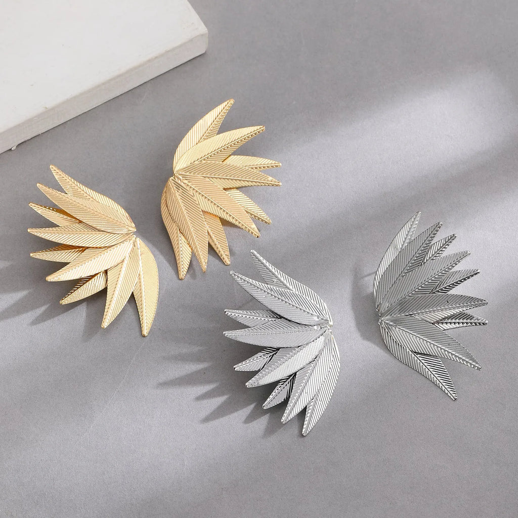 A pair of gold and white alloy patch earrings shaped like leaves.