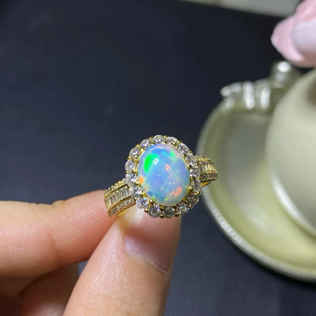 Adjustable opening opal ring in sterling silver with gold tone plating on a model's hand